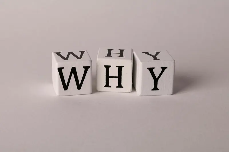 Three white letter blocks on a grey background spelling the word WHY.