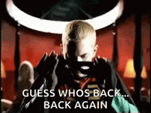 Eminiem is taking a picture of himself and says `` guess whos back … back again ‘’.